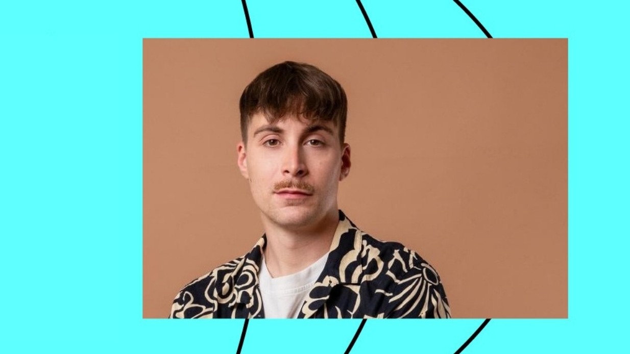 Muž v košili s krátkými vlasy a knírkem.