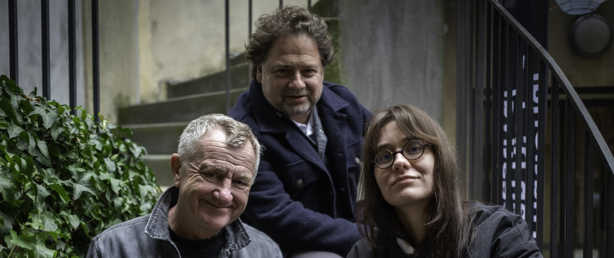 Tři osoby sedí na schodišti.