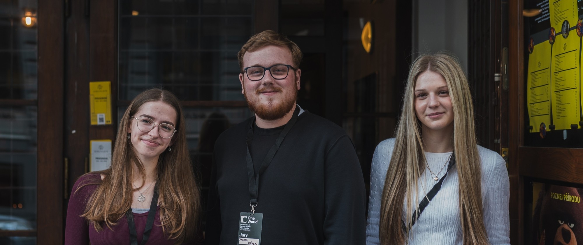 Tři osoby stojí vedle sebe před vchodem do kina.