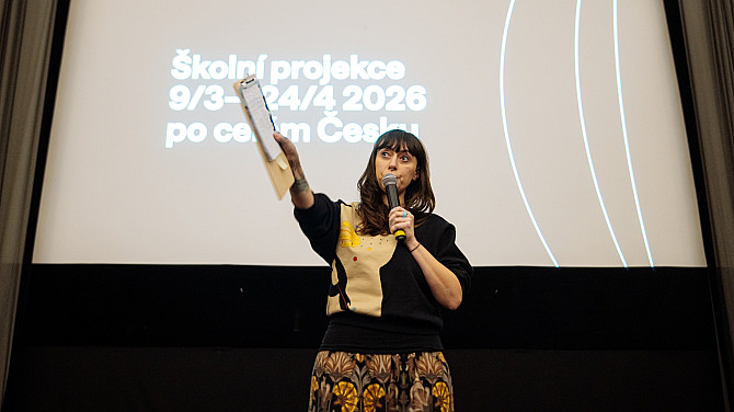 5. den Jednoho světa Žena stojí před plátnem, na kterém je napsáno Školní projekce 9/3 - 24/4 2026 po celém Česku, ukazuje a mluví k publiku do mikrofonu.