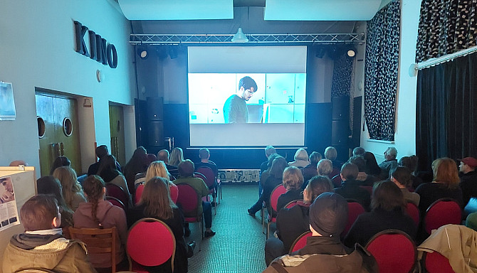 Festival Jeden svět - filmy a debaty zamíří do Telče již potřetí! Promítání filmu v menším sále s publikem sedícím na židlích, sledujícím projekci na plátně v Klubu Prostor v Telči.