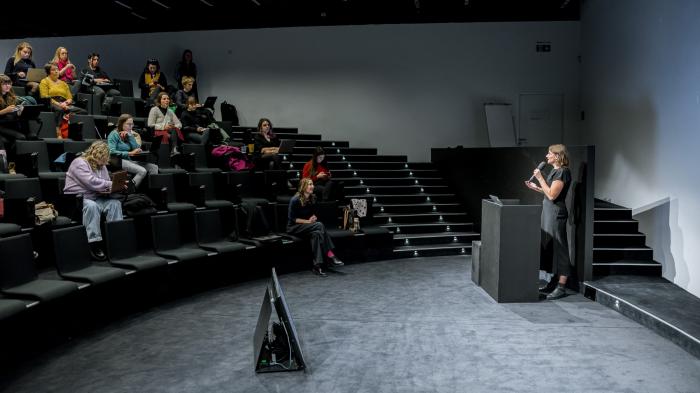 Žena mluví do mikrofonu a přednáší publiku.